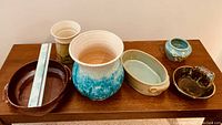 Six-piece collection of pottery on a wooden surface with a ruler for scale showing sizes.