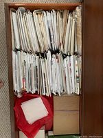 Overhead view of a drawer filled with over 50 sewing pattern envelopes, mostly white with vintage designs, arranged side-by-side and stacked.