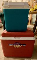 Two coolers stacked: a green extra tall cooler on top and a red large cooler beneath.