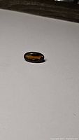 Oval cut deep color Madeira citrine gemstone placed on white surface, showing rich color and faceting
