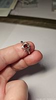 Front view of the artisan style ring showing deep red garnet center stone with surrounding purple amethyst accents held in a unique 925 sterling silver setting.