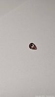 Pear-shaped padparadscha sapphire on white background showing overall shape