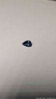 Photo of a natural deep blue pear cut London blue topaz gemstone, 1.24 carats, approximately 9x7mm in size, displayed on a plain neutral background to highlight stone clarity and cut.