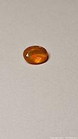 Close-up of natural Mexican fire opal in oval cut displaying its bright orange color and faceting on a neutral background.