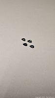 Four pear-cut natural blue-teal multicolored sapphires laid on a plain light surface.