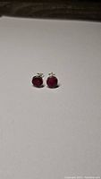 Pair of natural ruby stud earrings on white background showing size and shape