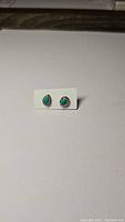 Pair of pear-shaped turquoise earrings shown side by side on white backing card