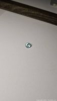 Aquamarine gemstone oval cut lying on a plain white surface, showing soft blue color and clarity.