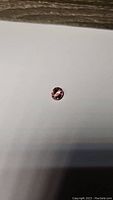 Clear close-up photo of oval cut bright pink tourmaline gemstone on a white background under natural lighting to show color and luster.