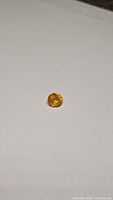 Close-up of the oval cut yellow sapphire on a plain background, showcasing color and shape.