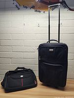 Both pieces of luggage together showing upright rolling suitcase and carry bag.