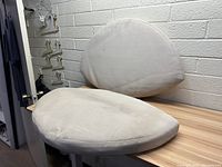 Two white outdoor patio cushions on a chair; one rounded seat cushion and one matching rounded back cushion.
