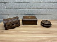 Front view of three vintage wood boxes placed side by side showing different shapes and designs.