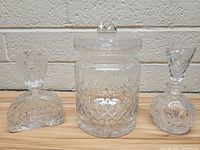 Front view of three clear glass decanters showing varying sizes and cut glass patterns with stoppers and lid.