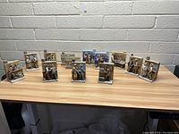 Full view of ten ceramic cologne decanters arranged on a table, each with detailed human figures and scenes.