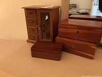 Four wooden jewelry boxes on dresser, including one with small drawers and a glass door with stained glass floral design