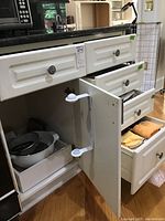Cabinet with open drawers showing multiple kitchen utensils and towels