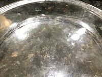 Close-up image showing embossed Pyrex logo on a clear glass pie plate indicating brand and authenticity.