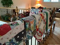 All six quilts draped over railing showing variety and size