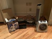 Photo of the lot showing all included items: Craig karaoke player box, Sony cassette recorder and boom box, Stoney boom box, portable heater, and air purifier on hardwood floor.