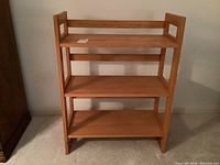 Front view of the wooden shelving unit showing three fixed shelves and its structure.