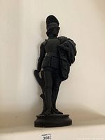 Frontal view of black ceramic conqueror statue showing the full figure with armor and helmet.