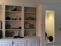 Photo of built-in shelves with decorative items including clocks, small statues, plates, and bowls