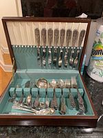 Full view of wooden chest open showing all flatware pieces in slots