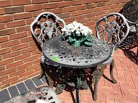 Overall view of the wrought iron table and two chairs set showing floral ornate design