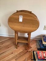 Close-up view of one tray in folded position resting in the stand, showcasing the oak finish and storage method.