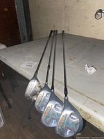 Photo of four golf club drivers with Wilson Ultra branding and head numbers 1, 3, 5, and a second 3 wood, placed on a table.