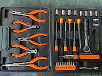 Two-part black plastic case holding multiple hand tools including pliers with orange handles on left and ratchet with sockets and bits on right.