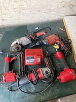 Photo showing all tools including angle grinder, nailers, drill, and charger.