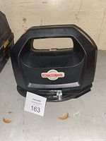 Front view of black Motomaster air compressor showing large handle, logo, and hose attachment area.