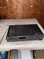 Top angled view of the black NAD receiver on a table showing ventilation pattern and surface wear.