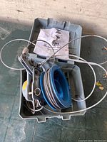 Plastic storage box containing pulley system components and folded instruction manual on inside lid.