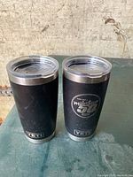 Two black Yeti Rambler tumblers side by side, one with 'milestone 354' logo and the other with 'GCN Town' logo, showing front views