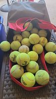 Bag with open top showing numerous used tennis balls inside.
