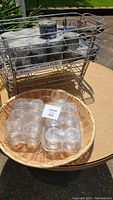 Metal wire rack filled with 10 cans of Power Heat chafing dish fuel, plastic covered small glass bowls on wicker tray.