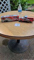 Photo of the die cast truck and bus collectible on a table next to a water bottle, showing the scale and condition