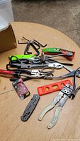 Overview of all tools on a wooden surface including knife, scissors, pliers, Allen keys, level, and container of pins