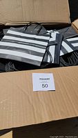 Box open showing many black and white striped Sephora bags with handles inside.