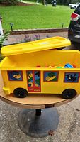 Yellow LEGO DUPLO dump truck storage bin with lid partially open showing assorted blocks inside