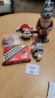 Full view of lot on round wooden table showing plush bulldog toy, ceramic figurine, bobblehead figurine, printed envelopes box and helmet decal.