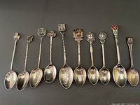 Full lineup of 10 sterling silver souvenir spoons laid out showing varied decorative handles and bowl inscriptions representing English, Irish, and Gibraltar origins.