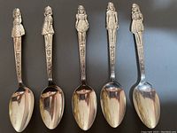 Full view of set 5 figural teaspoons depicting the Dionne Quintuplets with their names on the handles.