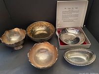 Five silver plated bowls arranged together showing the different bowl shapes and designs including footed bowls, repoussé bowl, and Tudor Rose shallow bowl in box.