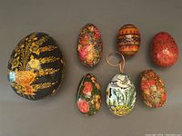 Front view of all 7 papier-mâché eggs showing various colorful floral and geometric patterns.