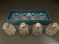 Photo showing set of 4 Birks salt and pepper shakers with sterling and mother-of-pearl lids in original blue box along with 4 separate shakers in front.