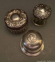 Three items: a round Birks Regency Plate ring box with lion crest on lid and black velvet interior, two small clear glass vanity jars with sterling silver lids, one monogrammed and damaged, the other highly embossed.